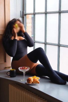 Stylish black girl in sexy lingerie standing by a large wooden post