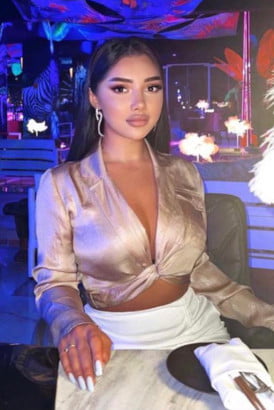 Young busty Turkish girl sitting at a table in a plush restaurant